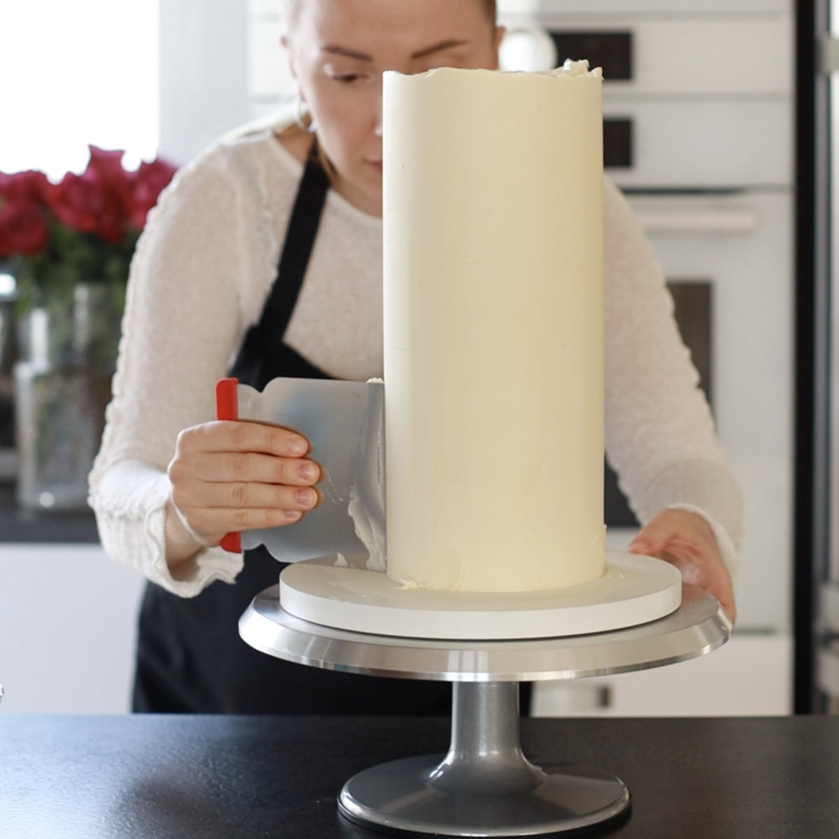 Hohe Torte beim Glätten auf einer weißen Hauptplatte